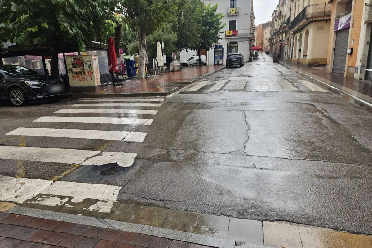 Calle del centro de Sant Sadurní d'Anoia con el asfalto mojado y casi sin gente, junto a un paso de peatones, durante la lluvia de la segunda jornada de la Escumostra