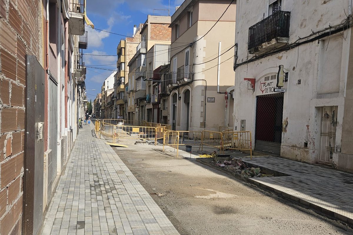 Calle Sant Pere de Vilafranca del Penedès en obras: acera nueva de adoquín gris con franja podotáctil, la calzada con la base extendida y vallas amarillas